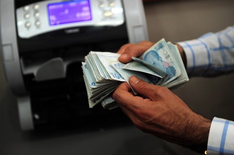 An exchange office worker counts Turkish lira banknotes in Istanbul on June 8, 2015. Turkish shares fell over 6 percent in morning trade and the lira plunged to a new record low against the dollar, as investors took fright at new political uncertainty following legislative elections. AFP PHOTO / OZAN KOSE / AFP PHOTO / OZAN KOSE